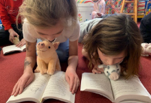 Two girls reading to plush pigs